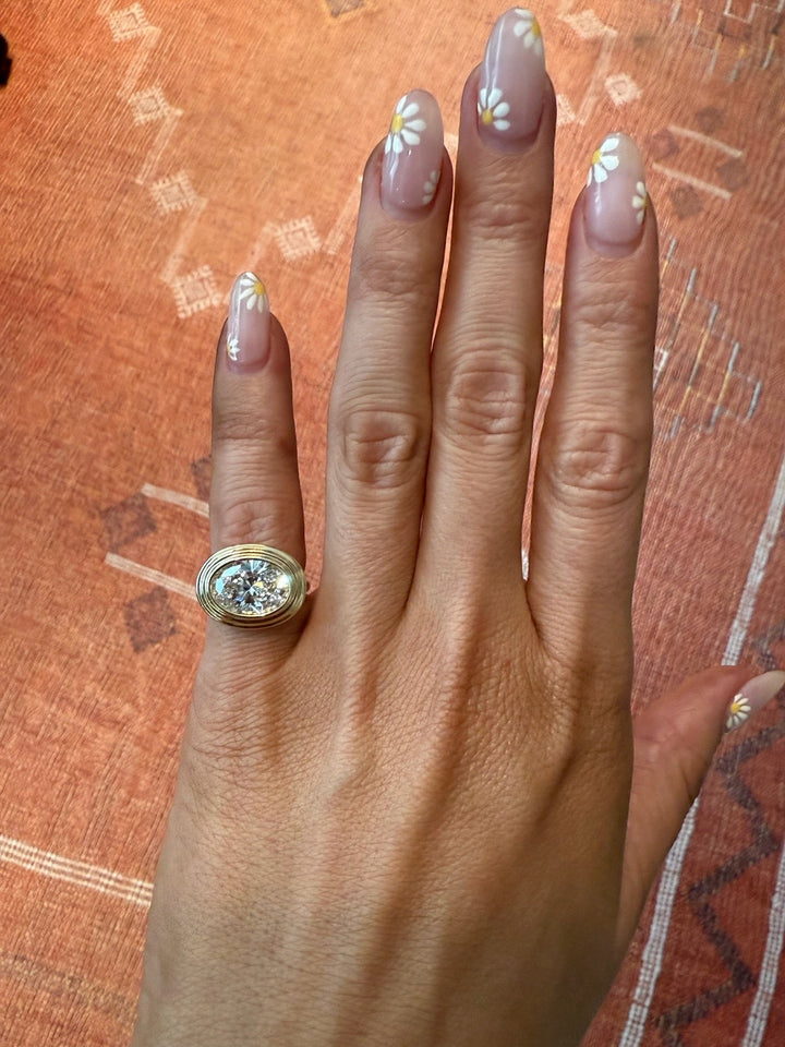 Hand wearing a gold ring with a diamond on a textured brown background